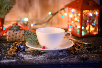 New Year holiday. Christmas decorations and spruce twigs on the table with a beautiful cup and a gift. White snow.