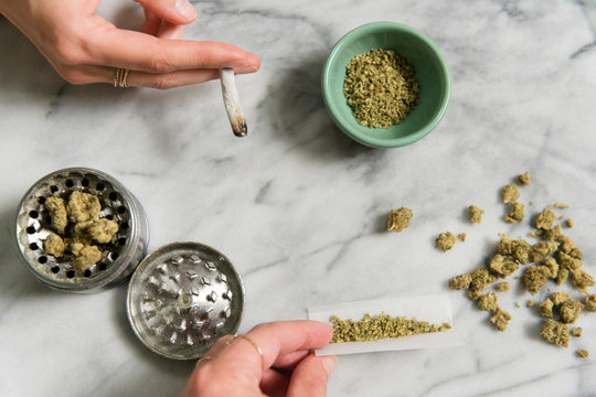 Hands of women rolling and smoking marijuana joints