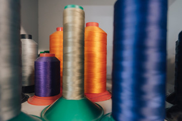 Close up detail shot of threads in a shelf. Sewing threads on a spool, yarn on plastic tubes. Material for sewing.