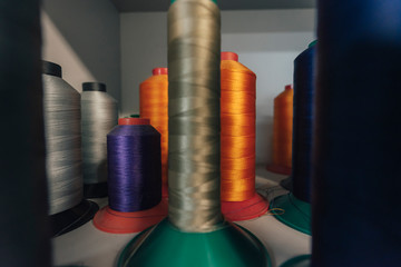 Close up detail shot of threads in a shelf. Sewing threads on a spool, yarn on plastic tubes. Material for sewing.