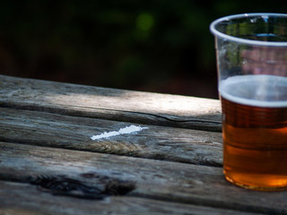 A line of cocaine on a wooden table with a glass of beer on the side