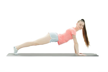 Young woman exercising - doing a plank in a studio