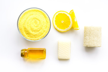 Lemon spa salt and spa assessories like soap, loofah, spa oil on white background top view