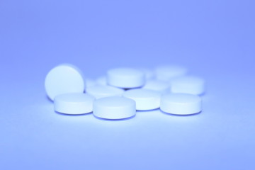 White pills on blue background. Close-up. Texture.