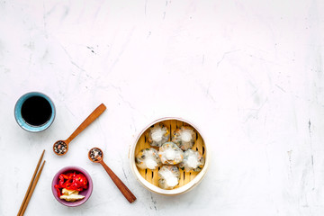 Dinner in Chinese restaurant with dim sum, sticks, spices and black tea on marble background top view space for text