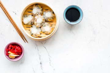 Dim sums with red pepper and vegetables with sticks and black tea in Chinese restaurant on marble background top view mockup