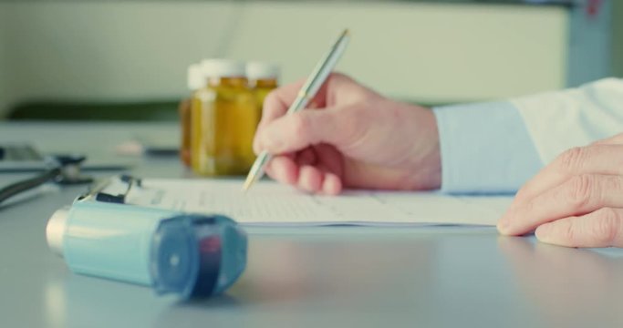 Doctor Filling Form On Clipboard By Inhaler On Desk 4K