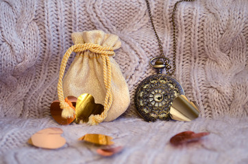 Composition for festive background with gift, pocket watch and hearts on knitted background