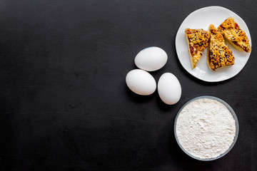 Ingredients for homemade cookies. Fresh cookies near flour, eggs on black background top view copy space