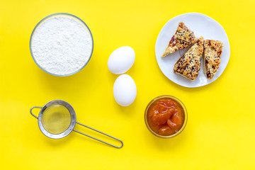 Cook cookies at home concept. Ingredients and instruments for make cookies. Fresh cookies near flour, eggs and sieve on yellow background top view