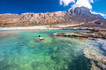 Young attractive man swimming in Balos lagoon on Crete island with azure clear water, Greece, Europe