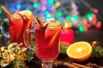 Mulled wine on a wooden background with candles, pine branches and Christmas lights. Selective focus