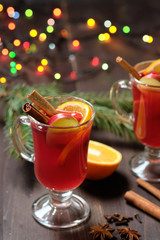 Mulled wine on a wooden background with candles, pine branches and Christmas lights. Selective focus