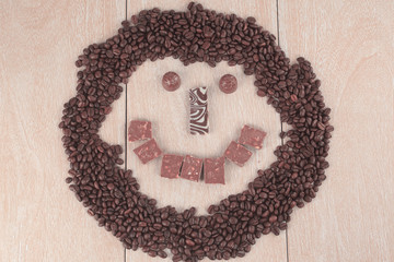 funny face from grains of black coffee and chocolate on wooden b