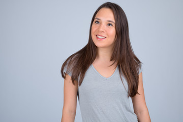 Fototapeta premium Young happy multi-ethnic woman smiling and thinking against white background