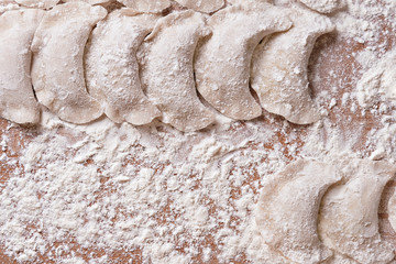 Dumplings with with potato on brown table sprinkled with flour