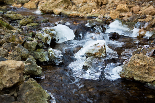 Nice photo of water flowing down a rocky creek through ice on a winter day.