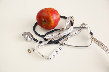 Apple, measuring tape and a stethoscope on the table