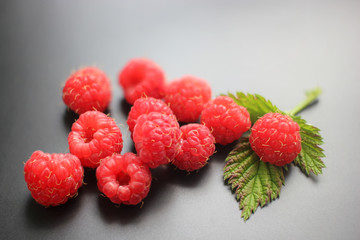 Ripe raspberries on the dark background, close-up, natural product of agriculture.