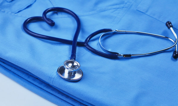 A stethoscope shaping a heart on a medical uniform, closeup, selective focus