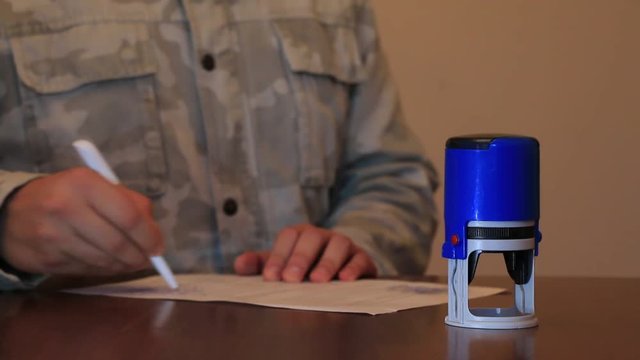 Man in uniform signing and putting stamp on documents