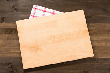 Cutting board and checkered tablecloth isolated on wooden background