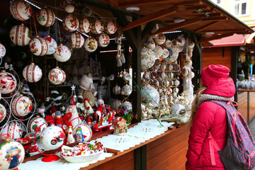 Little girl walking on Christmas market in Europe on holidays. Wooden multi-colored Christmas toys for decorating house at Xmas Market	