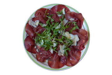 Flat lay. Piatto di bresaola con rucola e parmigiano sullo sfondo bianco. Cibo italiano.