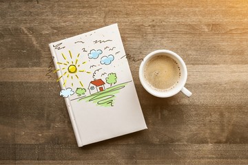 Cup of hot coffee with notebook on wooden table background, top