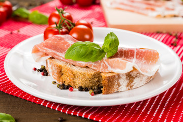 Plentiful table with bread, ham, white wine, tomatoes and ingredients