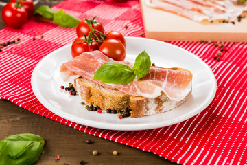 Plentiful table with bread, ham, white wine, tomatoes and ingredients