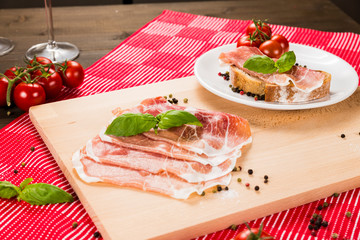 Plentiful table with bread, ham, white wine, tomatoes and ingredients