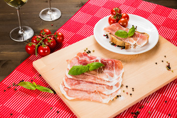 Plentiful table with bread, ham, white wine, tomatoes and ingredients