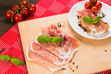 Plentiful table with bread, ham, white wine, tomatoes and ingredients