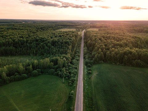 Aerial view of road amidst green landscape against sky in forest during sunset