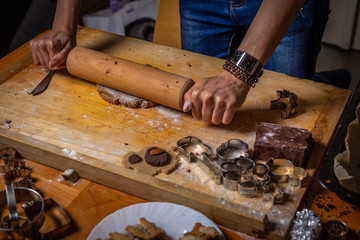 Close up on rolling gingerbread dough with forms, cutters and ingredients around