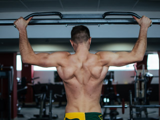 Fototapeta na wymiar Muscle man making pull-up on horizontal bar