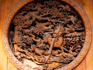Traditional, religious and symbolic chinese wood carving relief showing a dragon spitting water and trees in Jingan temple, Shanghai, China, Asia