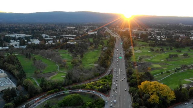 Aerial time lapse shot at sunset over the mountains above a freeway and golf course in California with cars below