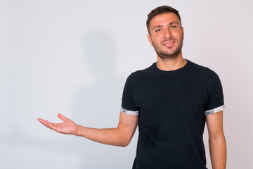 Naklejka premium Happy bearded Persian man smiling while showing something against white background