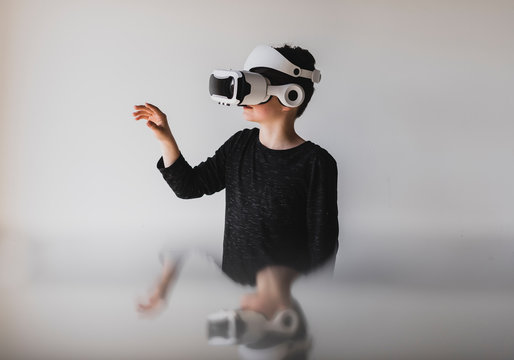 Boy gesturing while using virtual reality against white background