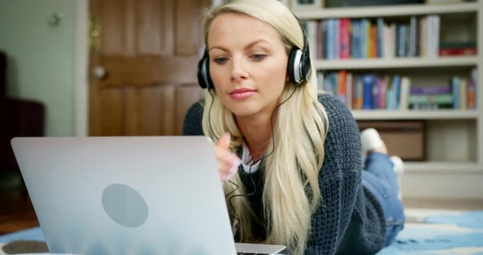Beautiful Blond Woman Lying On Rug Using Laptop