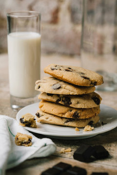 Close-up of stacked chocolate chip cookies in plate with milk on table