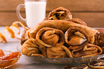 Hearty and delicious Breakfast. Rolls of pancakes with filling. Light wooden background.