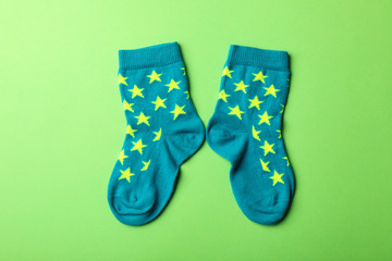 Pair of cute child socks on color background, top view