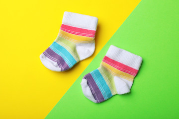 Pair of cute child socks on color background, top view