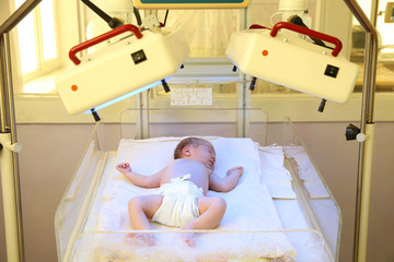 Newborn child under ultraviolet lamps in hospital