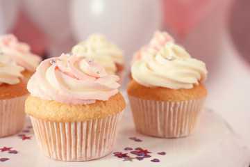 Stand with cupcakes and blurred balloons on background, closeup