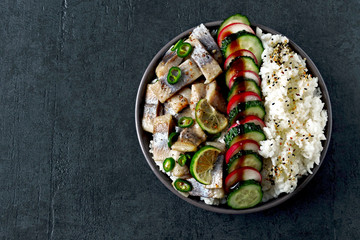 Poke bowl with herring, rice and vegetables. Herring poke bowl. Colorful healthy food.