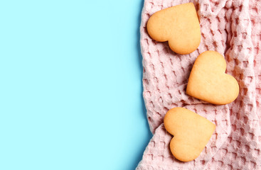 Homemade heart shaped cookies with napkin and space for text on color background, top view